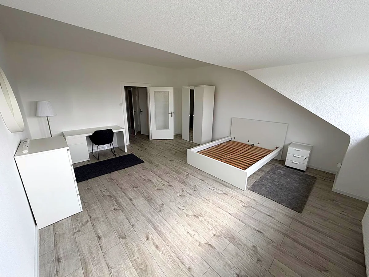 Möbliertes Zimmer mit Bett, Schreibtisch und Schrank